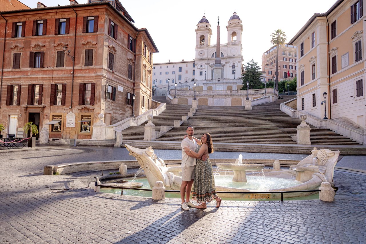 Couple embracing at the Spanish Steps fountain in Rome during golden hour sunlight
