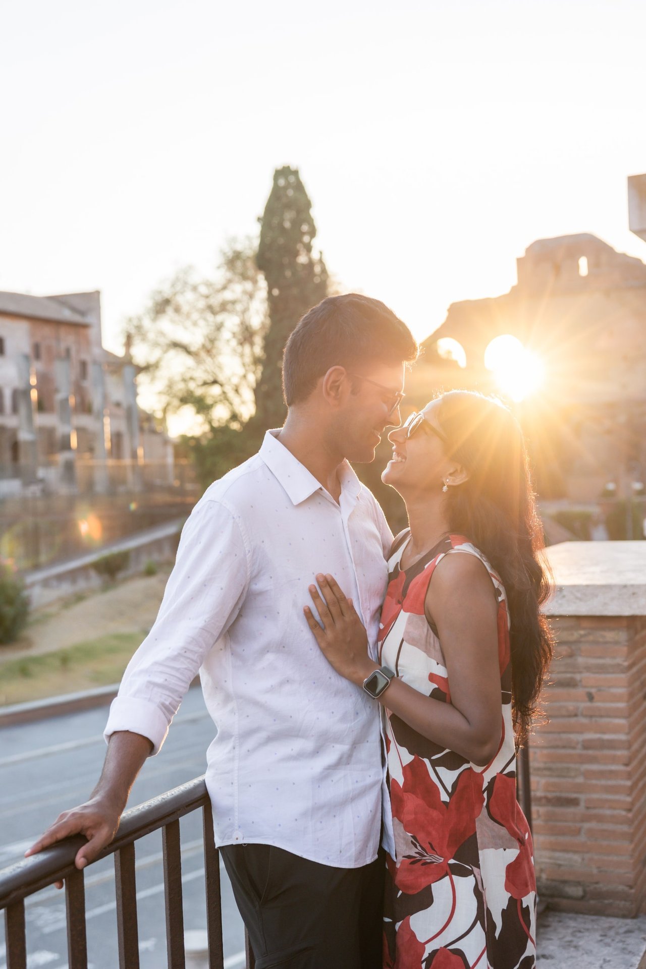 Couple embracing at sunset on a rooftop terrace overlooking historic Italian architecture and cypress trees