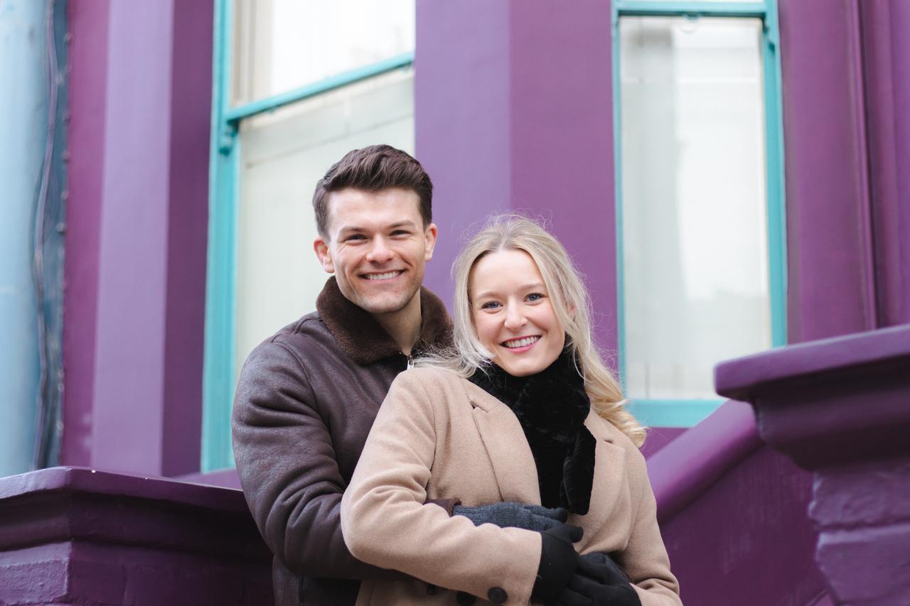 Couple posing together against vibrant purple and turquoise walls in bright daylight