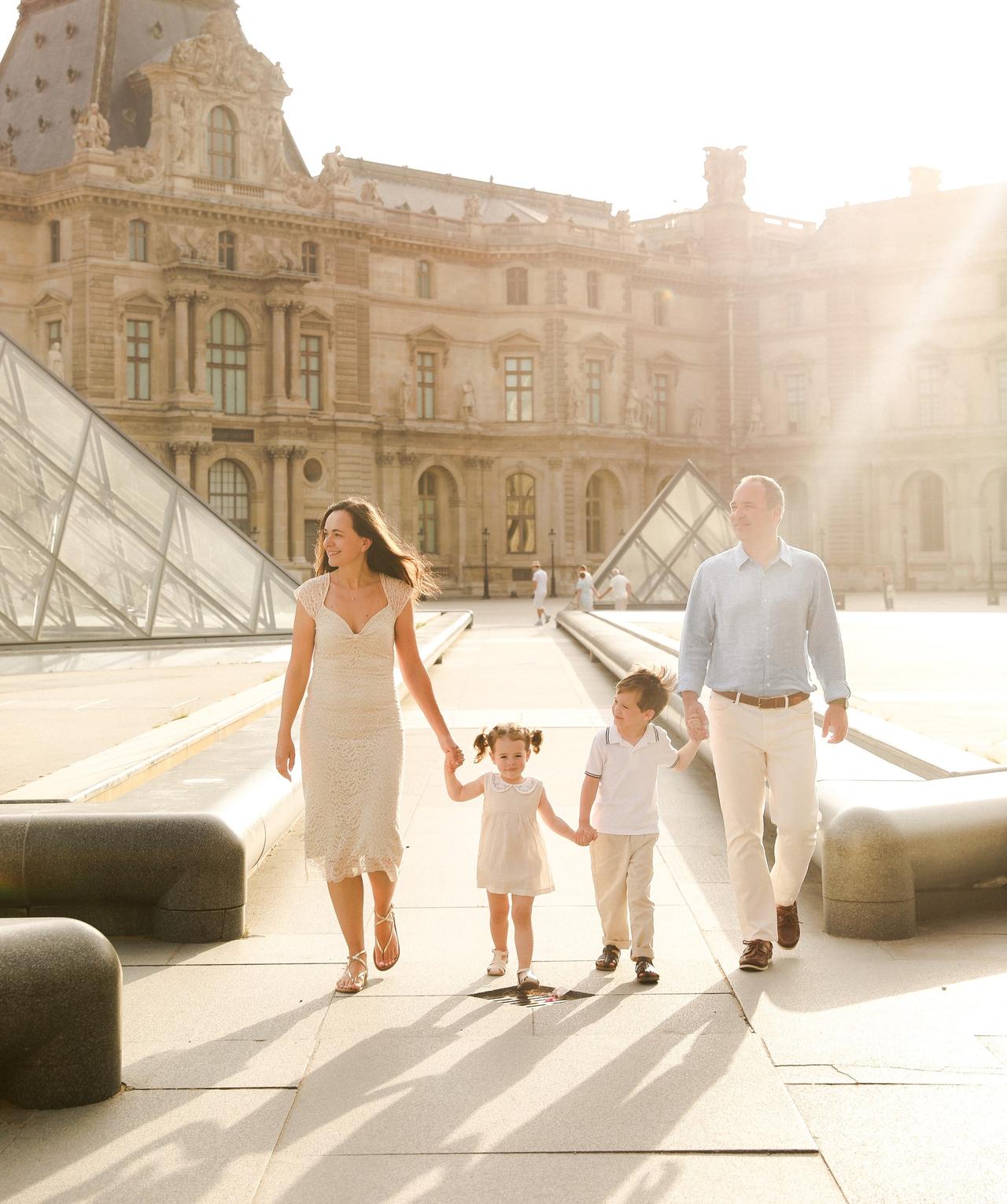 Family walking at the Louvre in golden morning light, Paris courtyard with glass pyramids behind