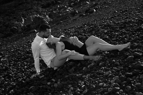 Couple relaxing on pebble beach at Playa La Arena in black and white during daytime