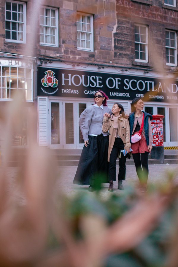 Three women walking past House of Scotland storefront in Edinburgh's old town during daytime