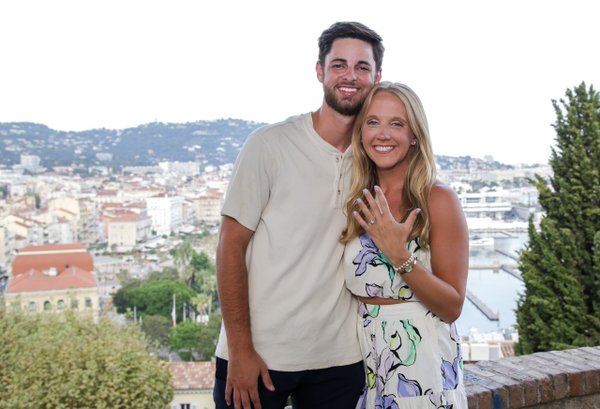 Couple smiling at a scenic overlook with Cannes cityscape and Mediterranean coastline behind them