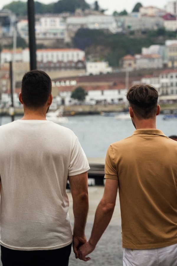 Two men holding hands overlooking the Douro River and Ribeira waterfront in Porto