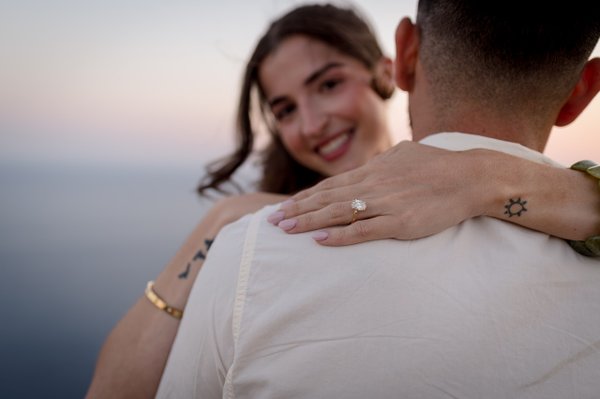 Engaged couple embracing at sunset overlooking the Adriatic Sea, woman's diamond ring visible