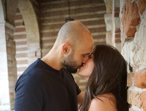 Couple kissing inside a historic brick archway in Verona, Italy during daytime