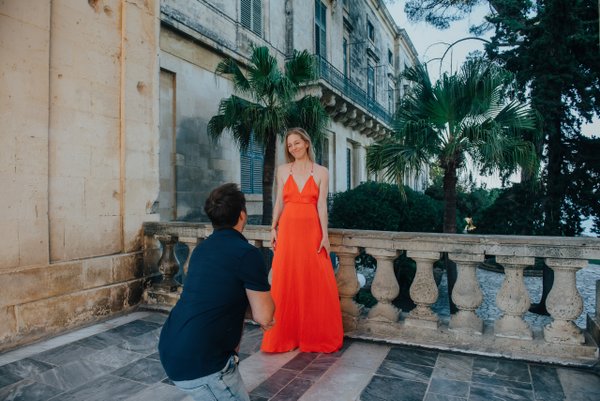 Couple posing at a stone balcony with palm trees and neoclassical architecture in Corfu's old town