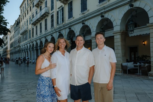 Group of four adults posing at Spianada Square in Corfu with classical arcaded buildings in evening light