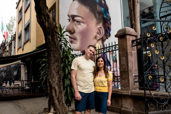 Young couple posing together in front of a large mural in Coyoacán, Mexico City during daytime