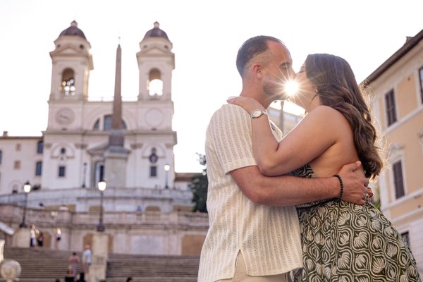 Couple kissing at sunset in front of the Spanish Steps church in Rome