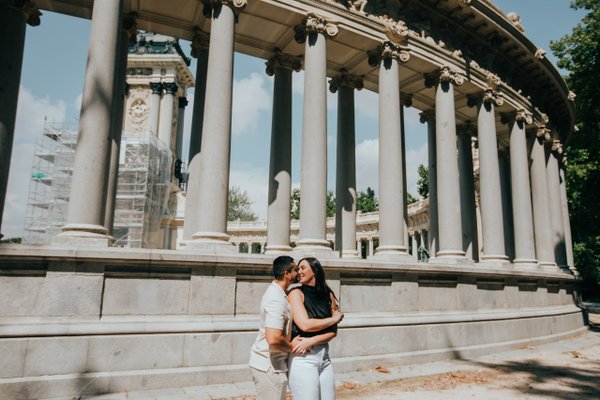 couple kissing beneath classical columns at Madrid's neoclassical building during daytime