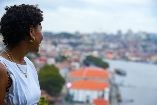 Solo traveler overlooking Porto cityscape and river from hilltop viewpoint during daytime