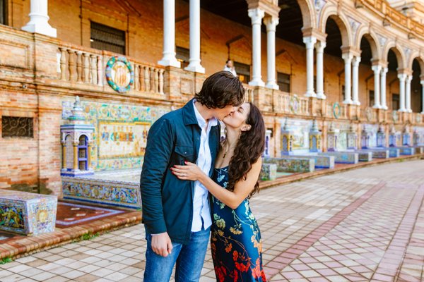 couple kissing at plaza de españa with ornate azulejo tiles and colonial architecture in sevilla