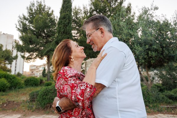 Middle-aged couple embracing among cypress trees and historic architecture in golden afternoon light