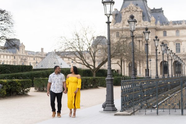 couple strolling past ornate lampposts and Parisian architecture in Jardin du Luxembourg during daytime