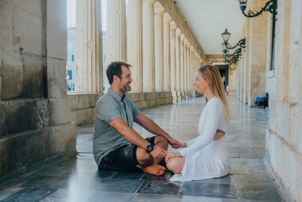 Couple sitting together in a classical colonnade with stone columns and elegant architecture in daylight