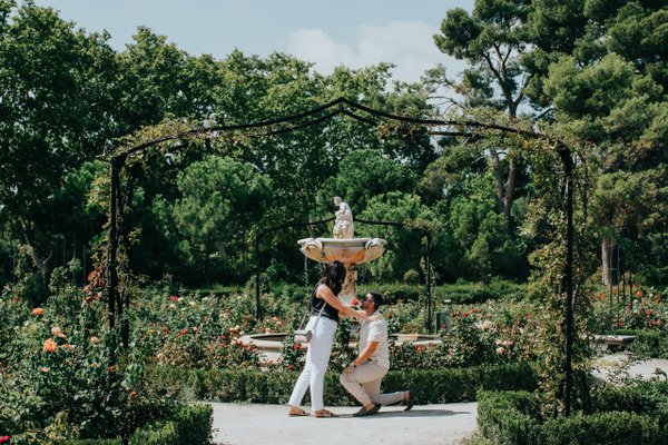 Couple embracing under a garden pergola during romantic photoshoot in Madrid with blooming roses