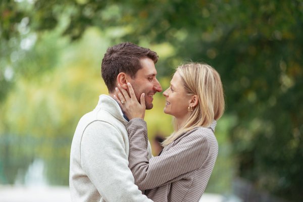 couple smiling face to face among blurred green foliage in soft daylight