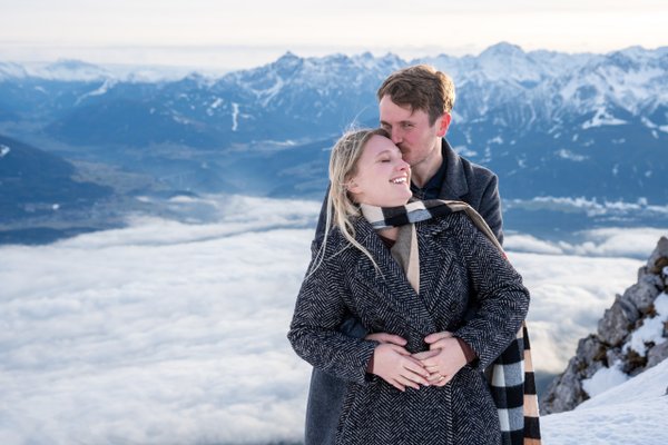 Couple embracing on snowy Innsbruck mountaintop above clouds, Nordkette winter photoshoot