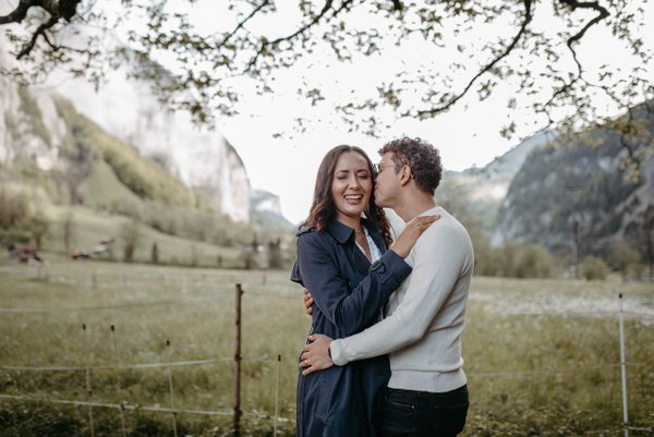 Couple embracing under blooming trees in a mountain valley with steep cliffs in Interlaken