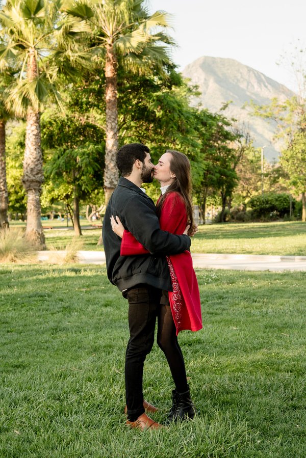 Couple embracing in Parque Bicentenario with palm trees and mountain backdrop during daytime