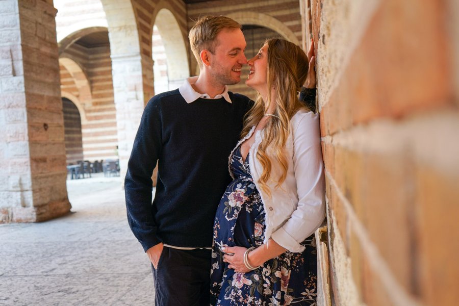 Couple kissing in a Renaissance arcade with terracotta arches in Verona during daytime