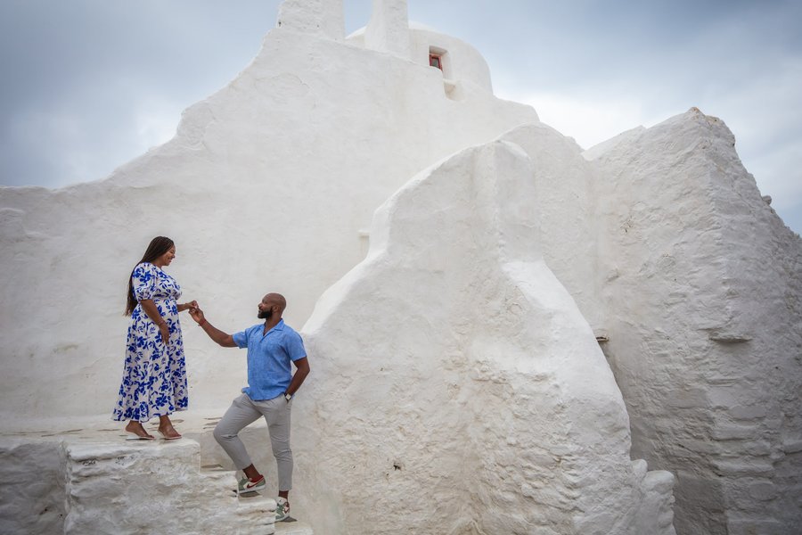 Couple posing at whitewashed Paraportiani Church in Mykonos during daytime photoshoot