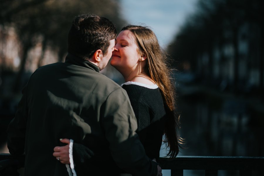 Couple kissing on a sunny day in a tree-lined street in Utrecht, backlit morning light