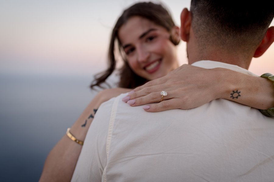 Engaged couple embracing at sunset overlooking the Adriatic Sea, woman's diamond ring visible