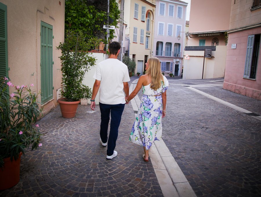 Couple jogging through a charming Mediterranean alley with pink buildings and ivy-covered walls in daylight