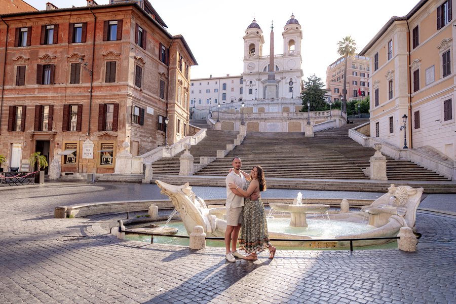 Couple embracing at the Spanish Steps fountain in Rome during golden hour sunlight
