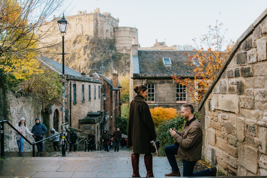 couple standing in historic edinburgh street with castle looming in autumn light
