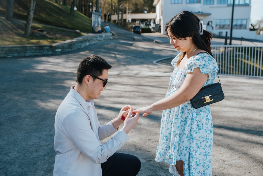 Man proposing to woman with ring on sunny Oslo street in bright daylight