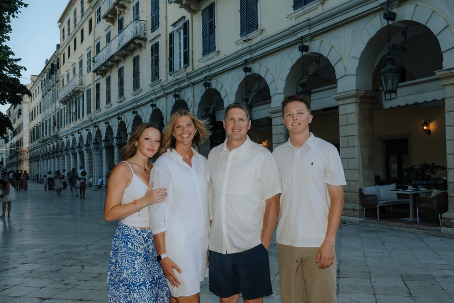Group of four adults posing at Spianada Square in Corfu with classical arcaded buildings in evening light