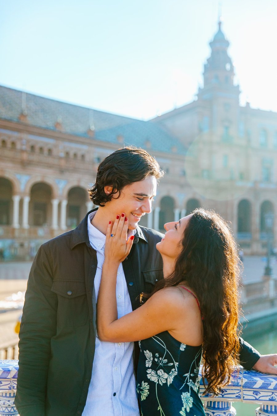 couple smiling in golden sunlight at historic Plaza de España in Sevilla with ornate architecture and tower