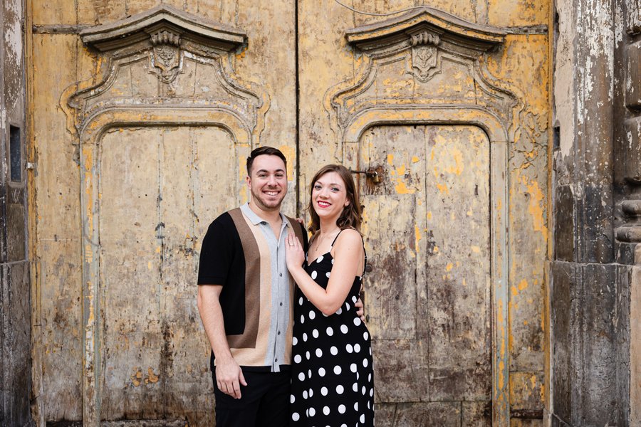 Couple smiling in front of ornate weathered golden doors in historic Palermo