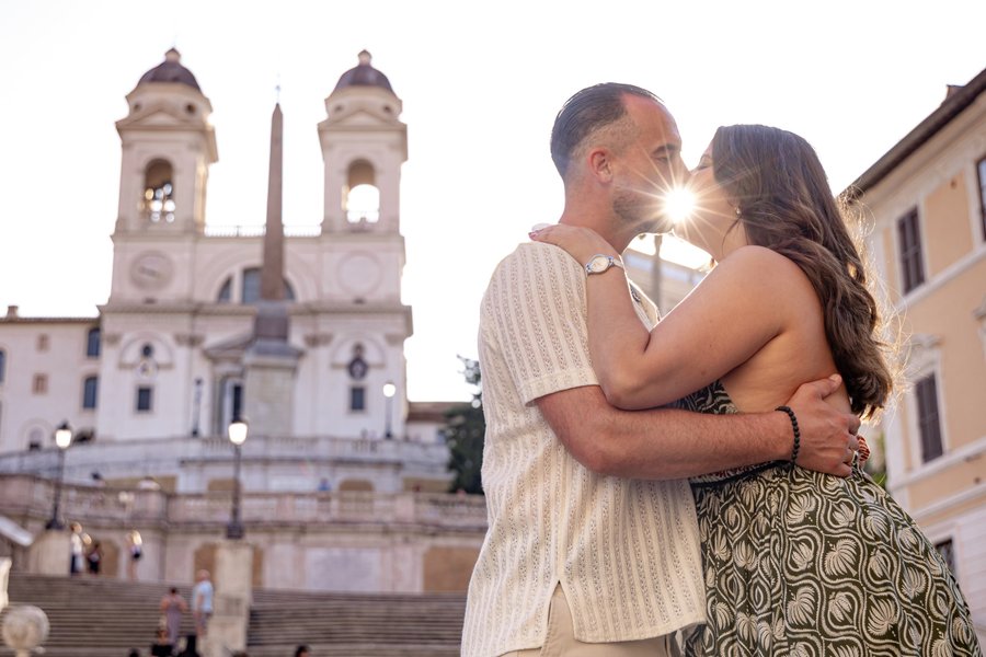 Couple kissing at sunset in front of the Spanish Steps church in Rome