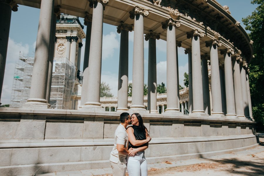 couple kissing beneath classical columns at Madrid's neoclassical building during daytime