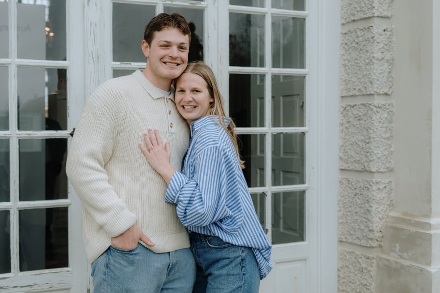 Young couple smiling together outside a white-trimmed building in Munich during daytime
