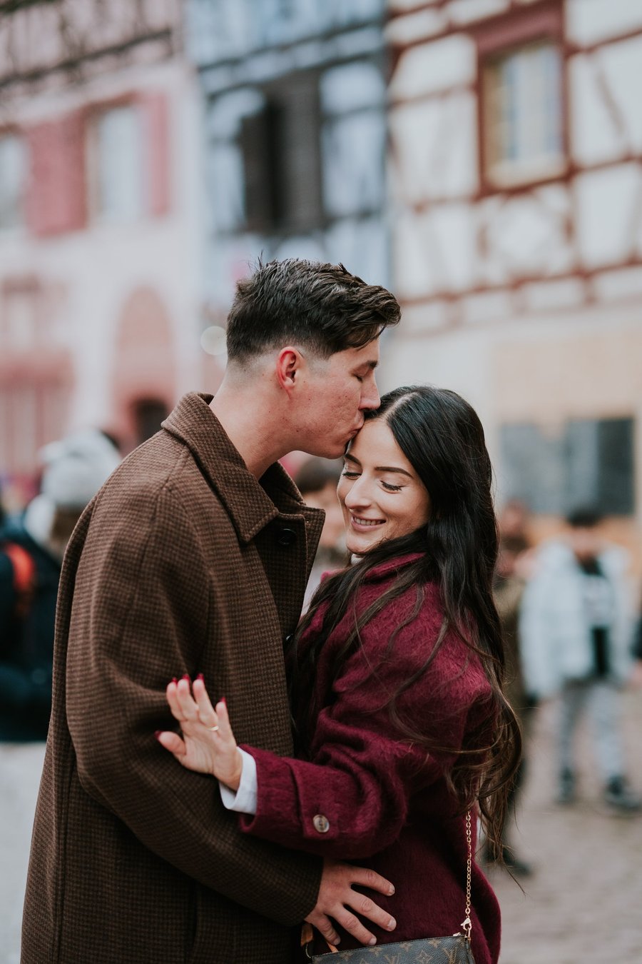 couple kissing in front of historic brick buildings during daytime in colmar
