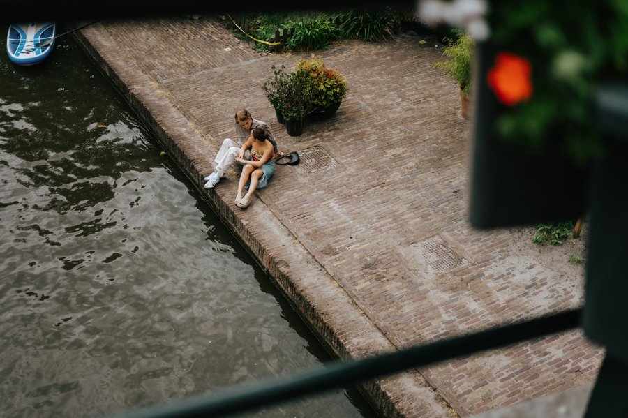 couple sitting on brick waterside quay during daytime in Utrecht