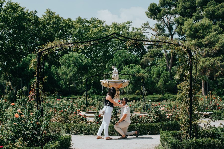 Couple embracing under a garden pergola during romantic photoshoot in Madrid with blooming roses
