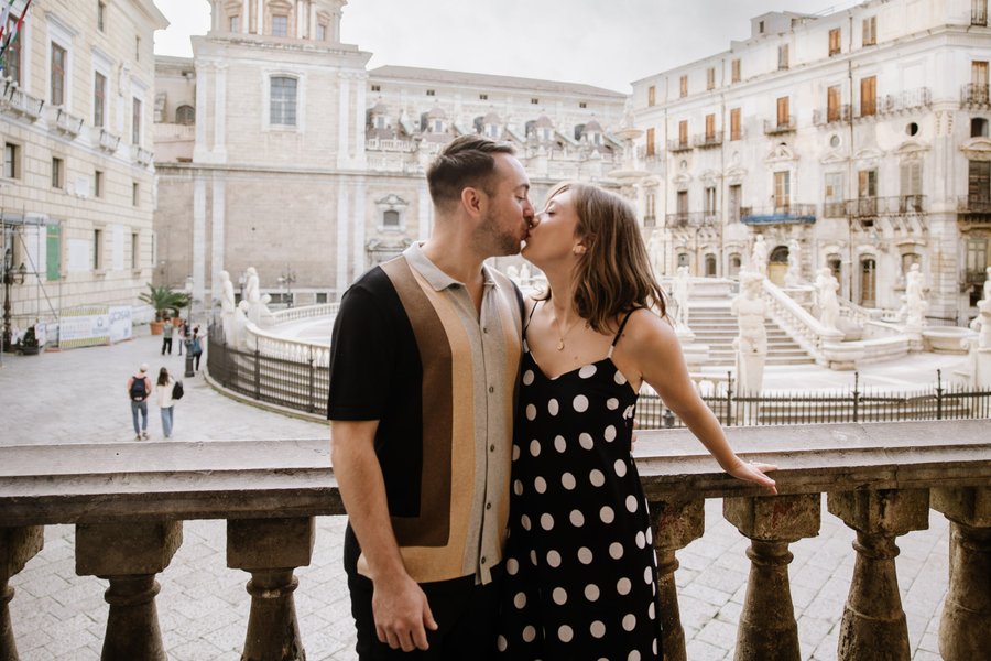 couple kissing at fontana pretoria with baroque architecture and plaza in palermo, sicily