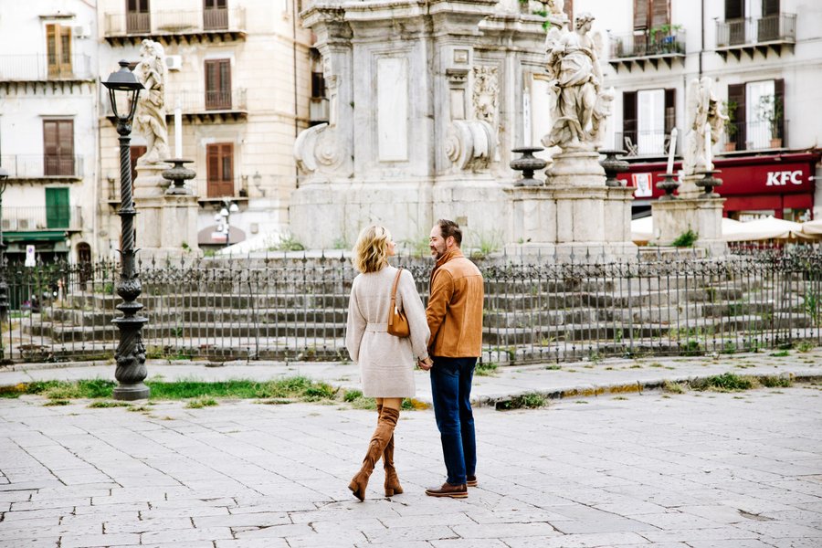 Couple holding hands in Palermo's historic square with baroque fountains and classical architecture