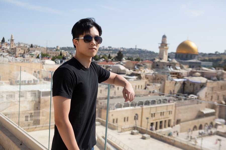 Solo traveler overlooking Jerusalem's Old City skyline with the golden Dome of the Rock in bright daylight