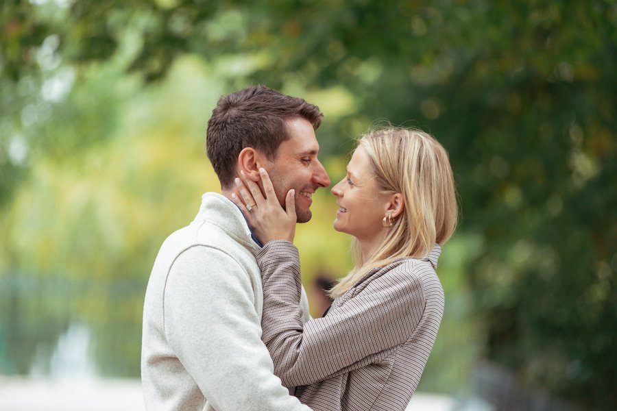 couple smiling face to face among blurred green foliage in soft daylight