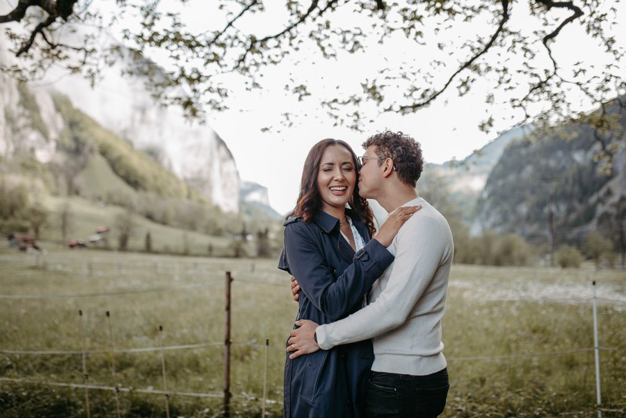 Couple embracing under blooming trees in a mountain valley with steep cliffs in Interlaken