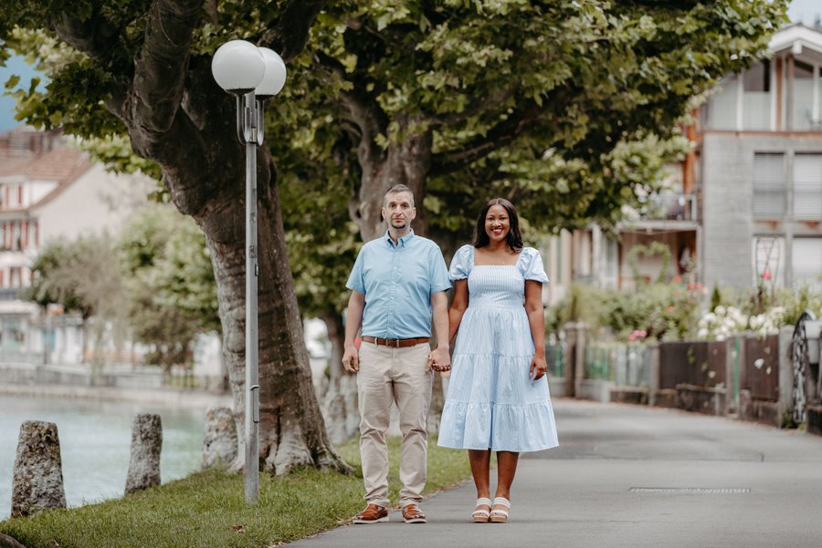 Couple holding hands on tree-lined street in interlaken during daytime