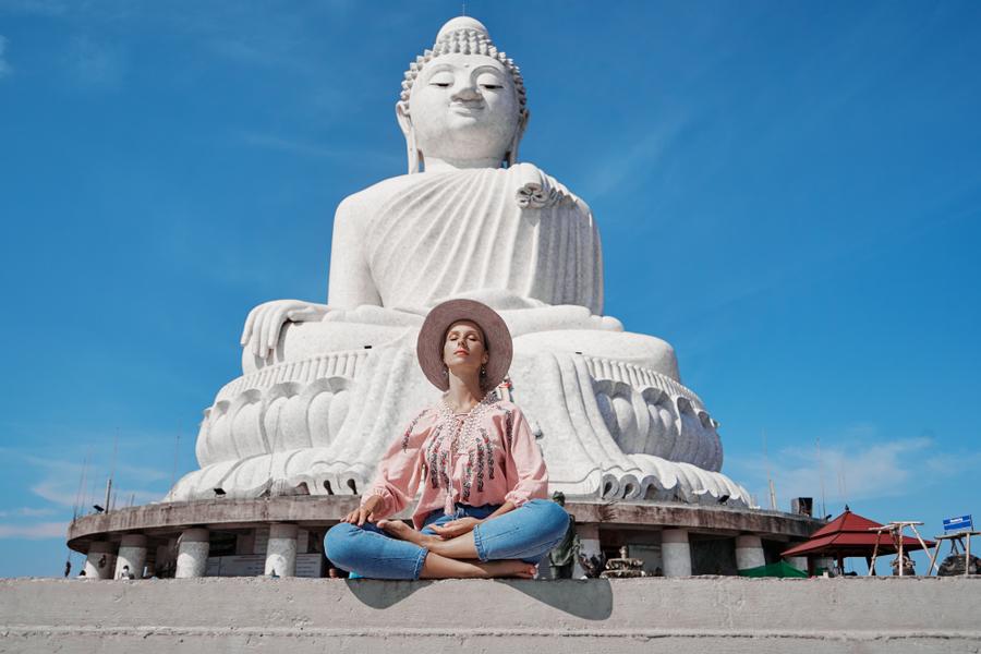 Solo traveler posing at the Big Buddha statue in Phuket under clear blue skies
